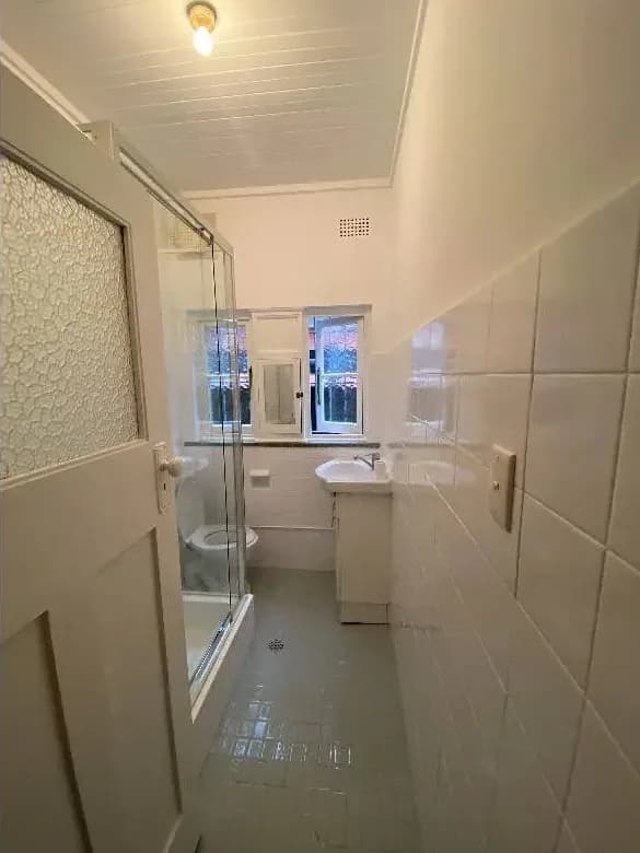 The same bathroom with the timber ceiling and the walls painted white, brightening the room end to end.