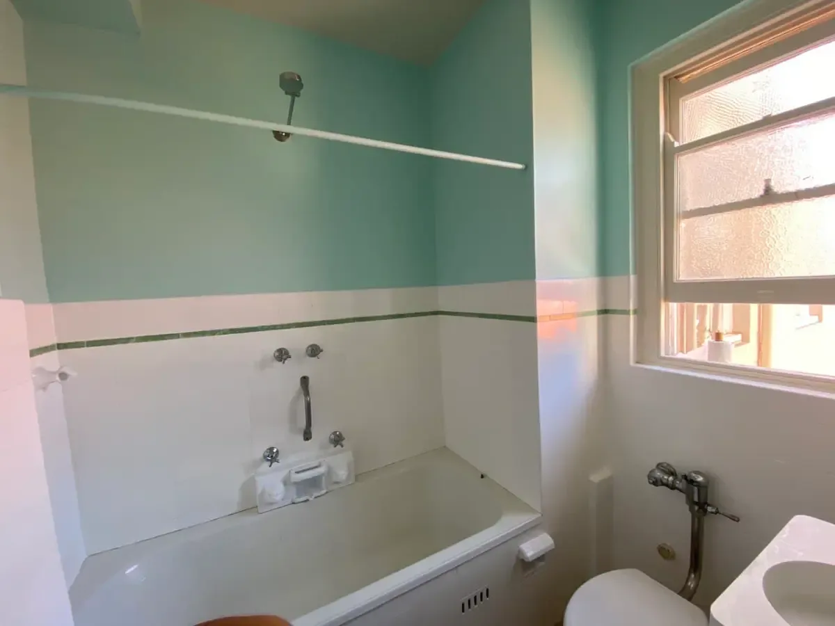 The same bathroom with the walls above the tiles repainted a soft mint green, picking up the green stripe in the tile border.