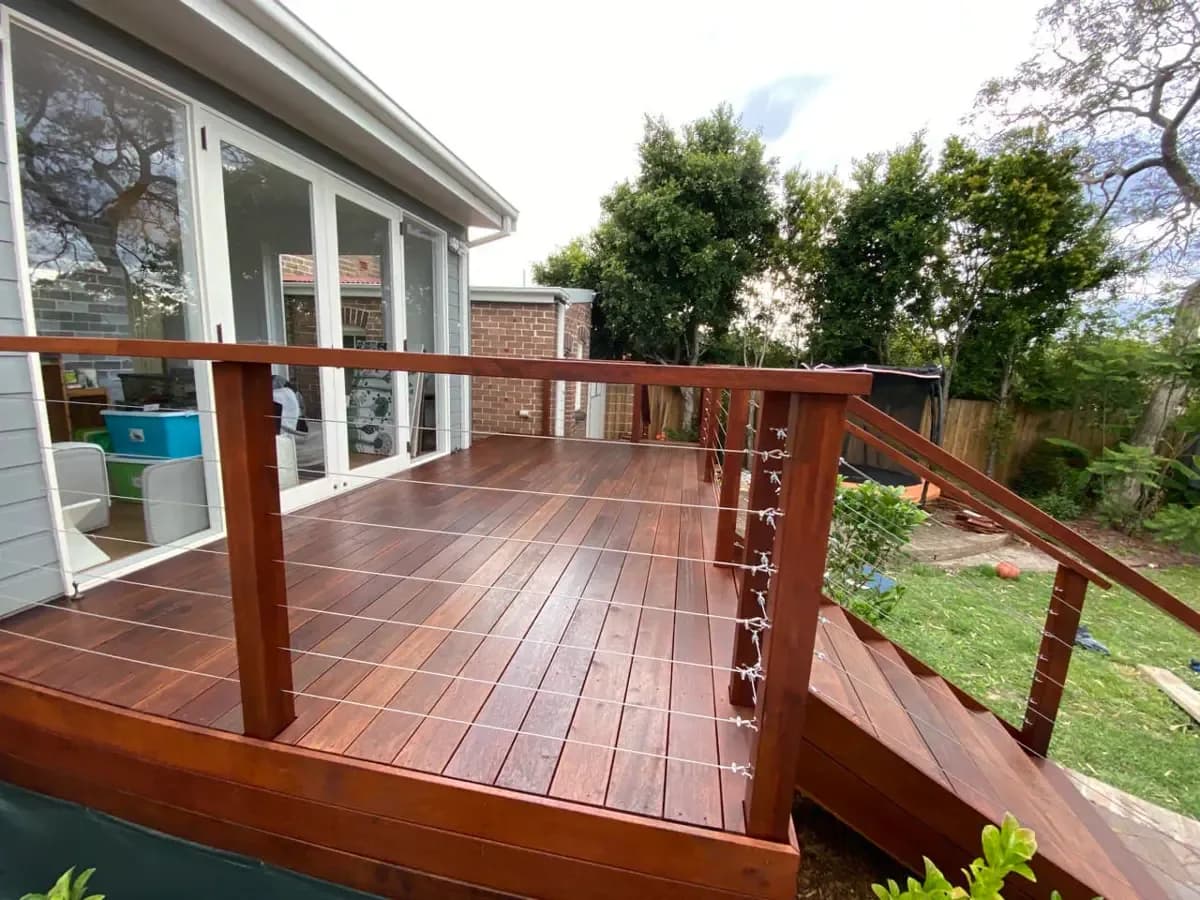 The same deck finished in a deep red-brown, with the timber balustrade and its wire infill complete and coated to match.