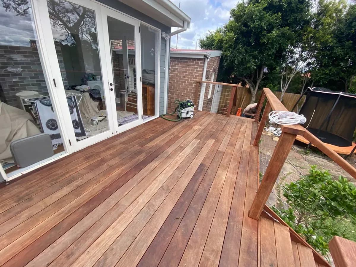 A raised timber deck with dull, dry boards, a dust extractor sitting on the surface and the balustrade posts only partly built.