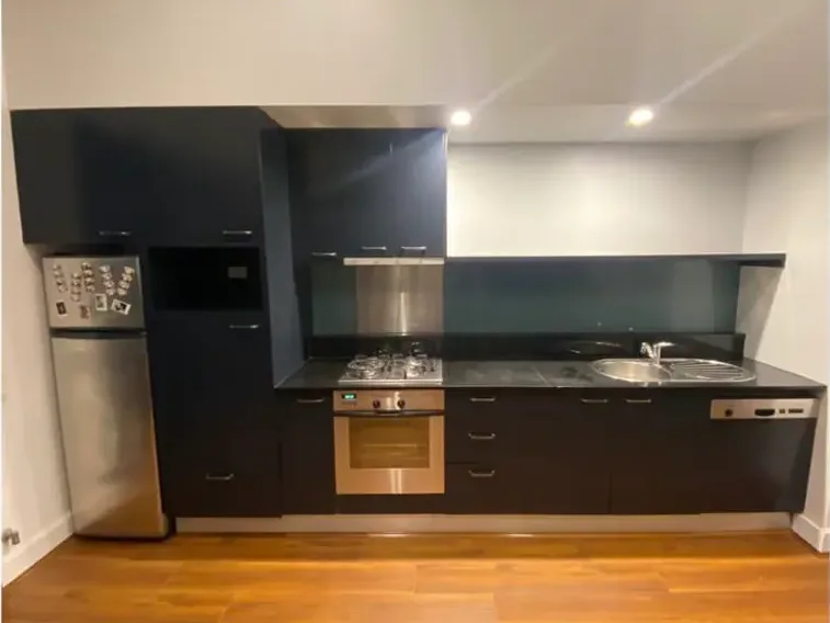 The same kitchen with every cabinet door and drawer front finished in flat black against white walls and ceiling.