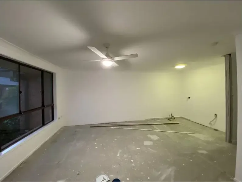 The same room with walls and ceiling finished in an even off-white, lit by the ceiling fan light, with the gear cleared away.