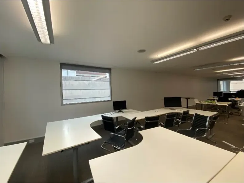 The same office with the wall repainted a light neutral, the desks set back out and the room noticeably brighter.