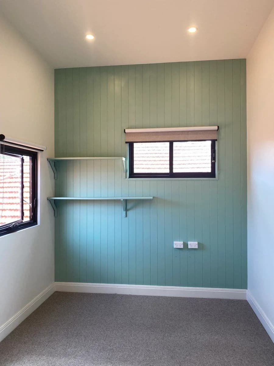 The same panelled wall repainted in soft sage green, with the shelves and brackets painted to match and crisp white surrounds.