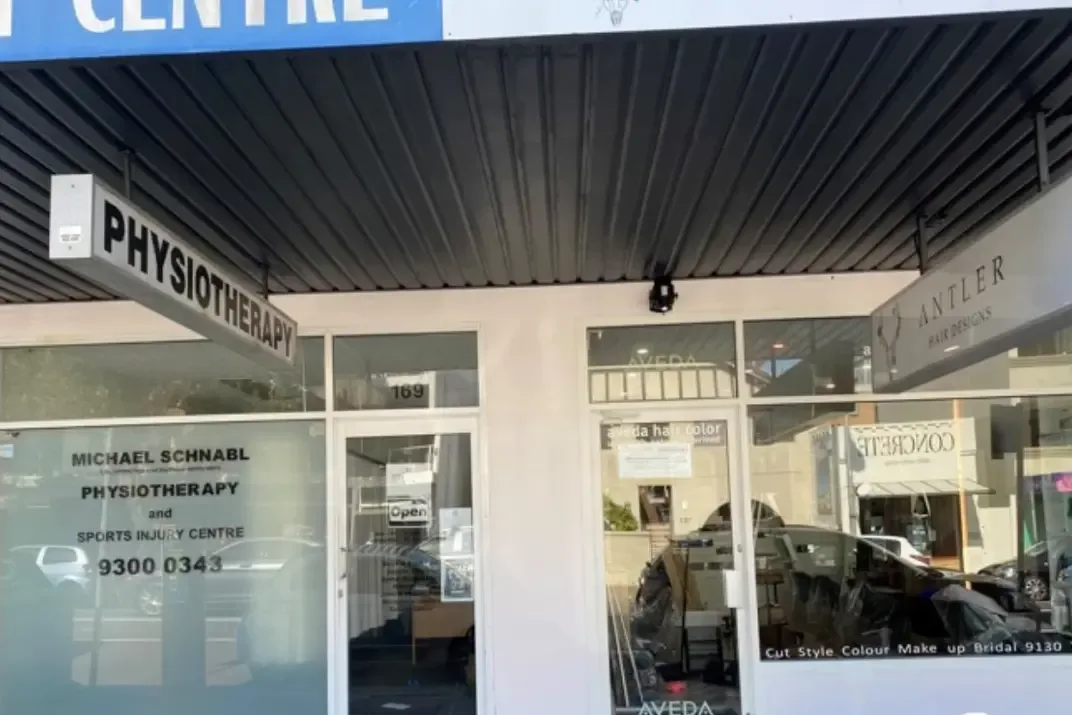 The same shopfront after painting, the render now a clean off-white with the awning soffit and beams finished in black.